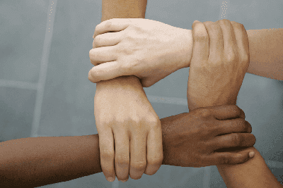 white and brown skinned hands clasped together